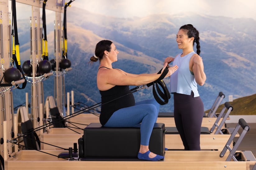 woman sitting on a reformer doing prenatal pilates