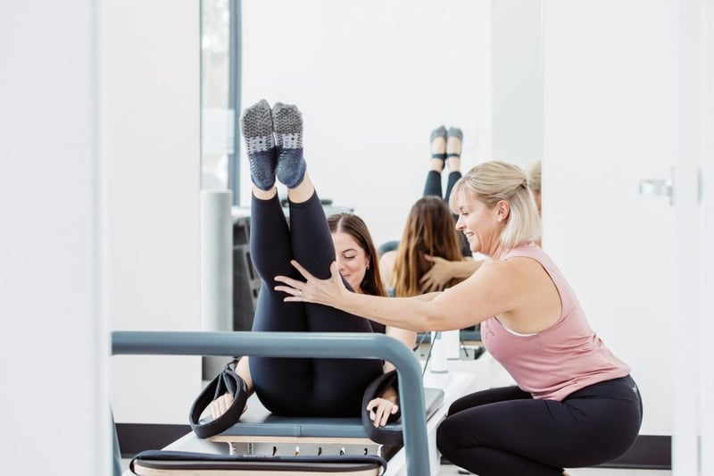 Pilates Exercises for Anyone - Club Pilates instructor helping member on reformer