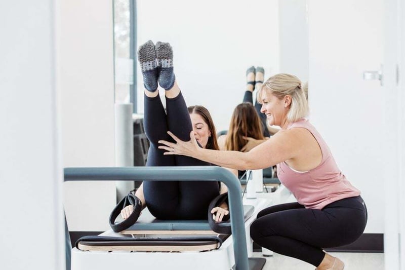 Reformer Pilates Sunshine Coast - Club Pilates member on a reformer being helped by instructor