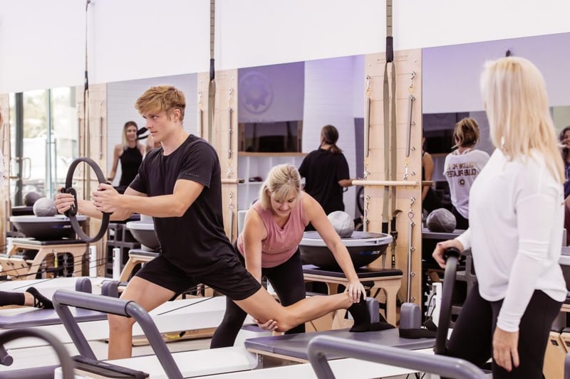 Why More Men are Starting Pilates - Club Pilates instructor helping male member in studio